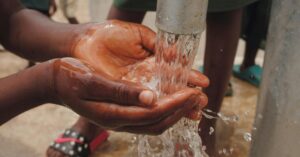 Hands capturing fresh water from a pump, highlighting cleanliness and resources.